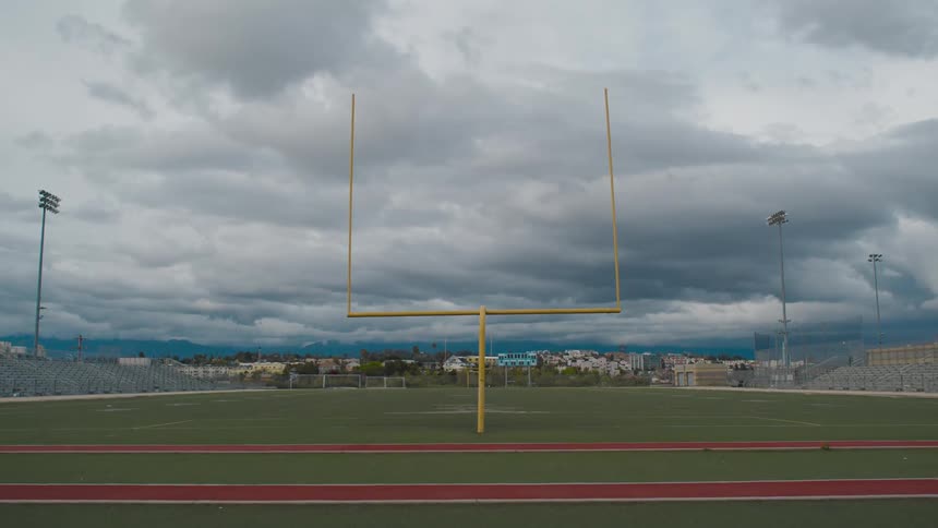 An empty football field with stands and track on a cloudy day