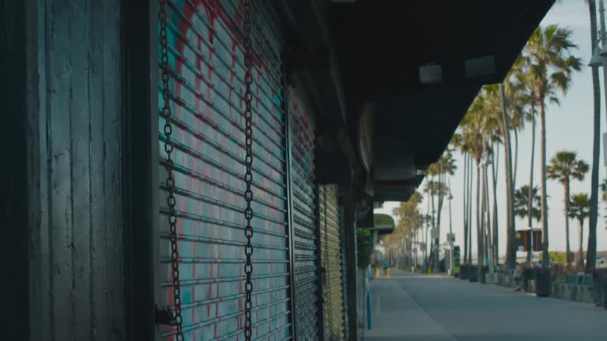 Rolling doors block the front of closed businesses in a park