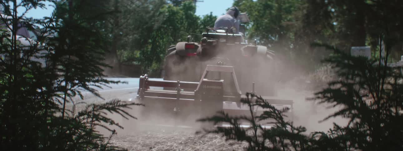 A person plowing the side of a road with a tractor