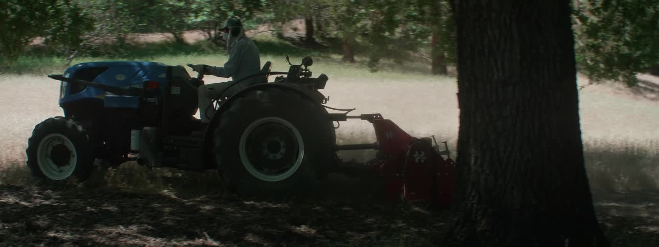 A person is riding on a tractor in a rural area