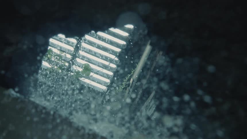 Water falls into a sewer grate during the day