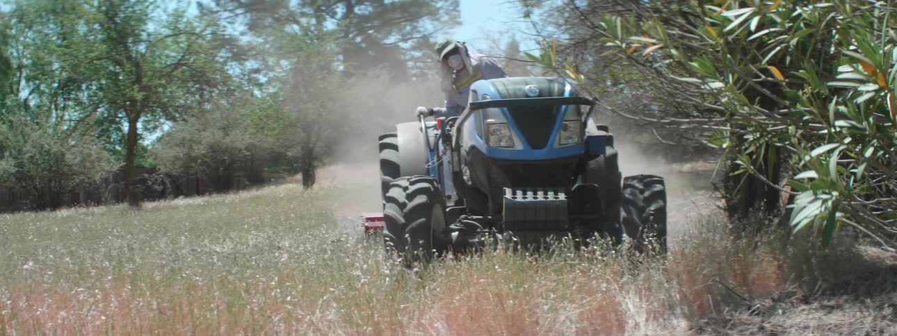 A person is driving a tractor in a field of grass