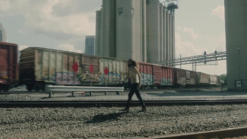 A person is walking by a moving train at dusk