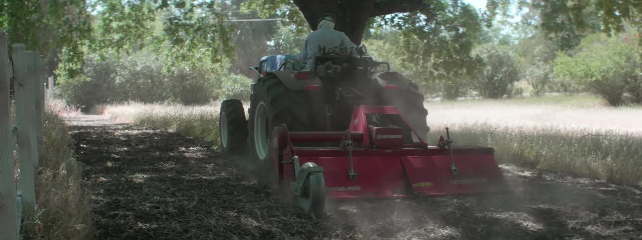 A person is running the tractor over the field