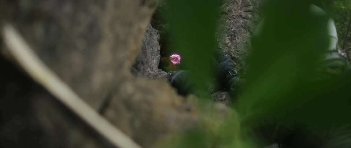 A man climbing up a hill reaching for something