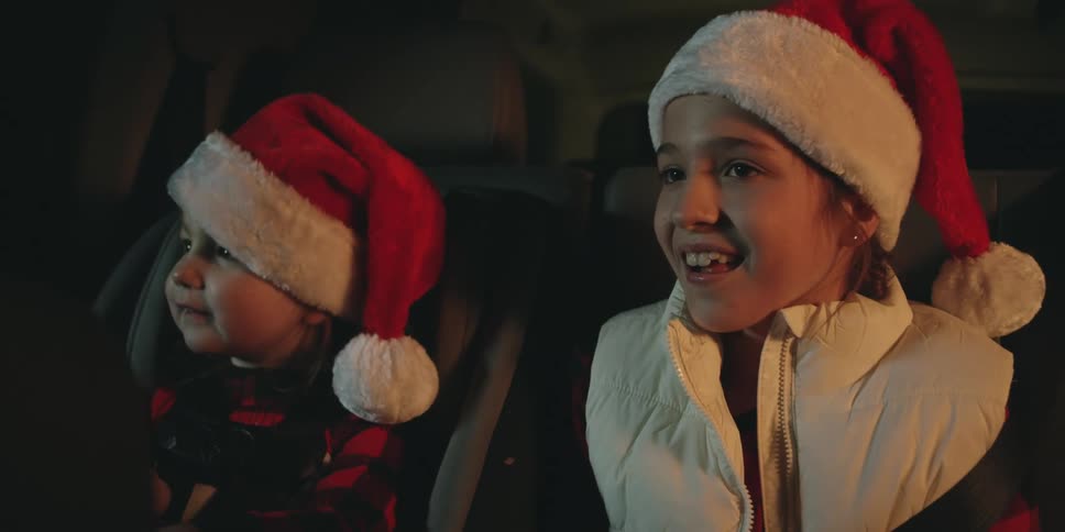 Two children point and clap at something from the car