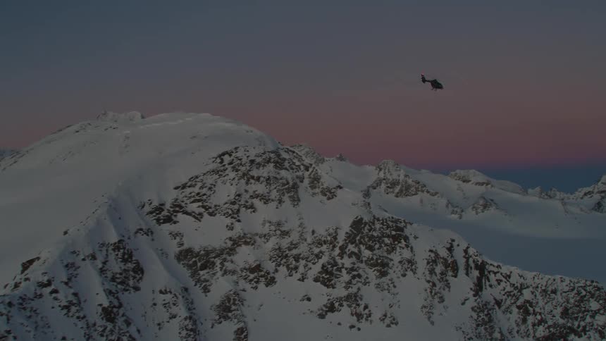 A view of a helicopter flying over a snowy mountain range