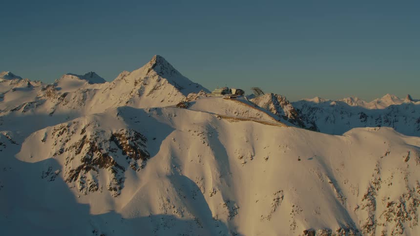 A ski lift building resort on top of a snow covered rocky ridge