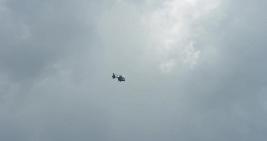 A helicopter passes a canyon and flies through dense clouds