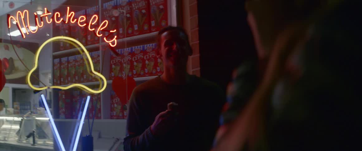 A man poses for a picture in front of an ice cream shop