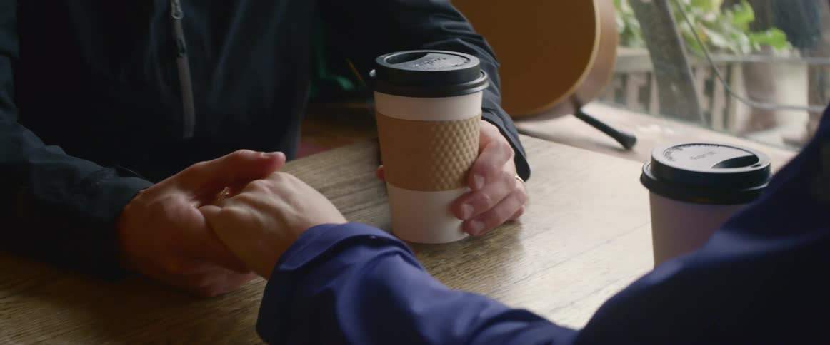 People hold hands at a cafe table
