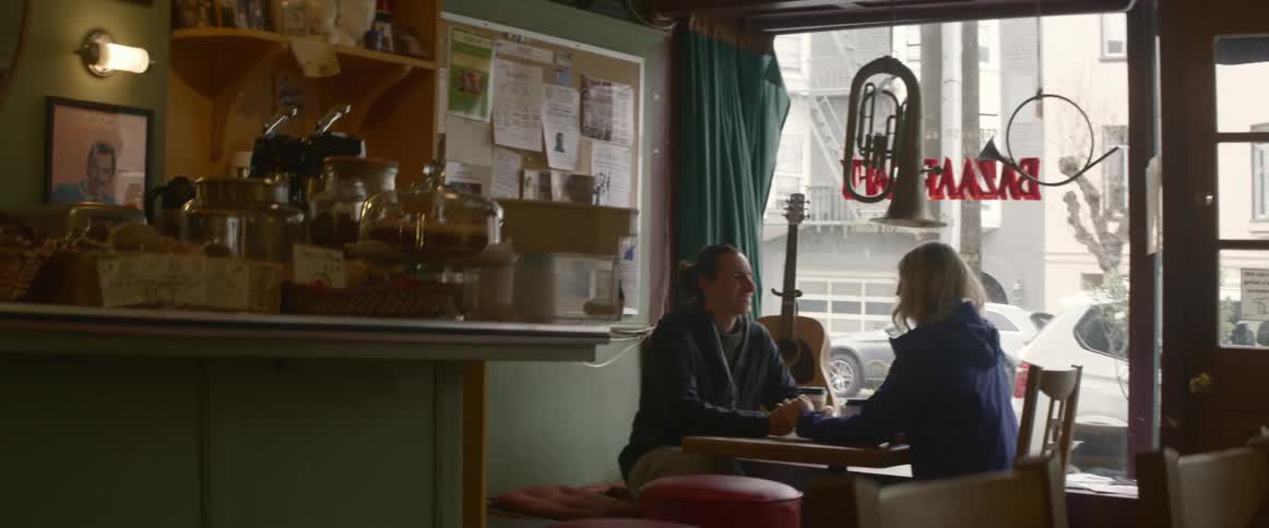 Two people sit in a coffee shop together talking