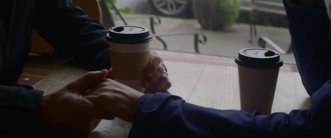 Two people are holding hands at a cafe