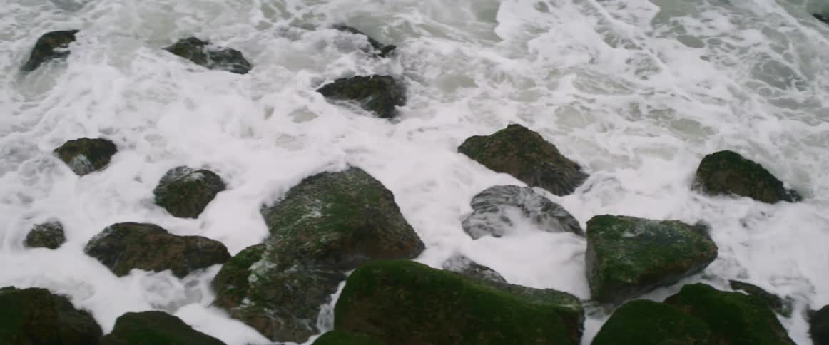 Waves crash against the rocks below