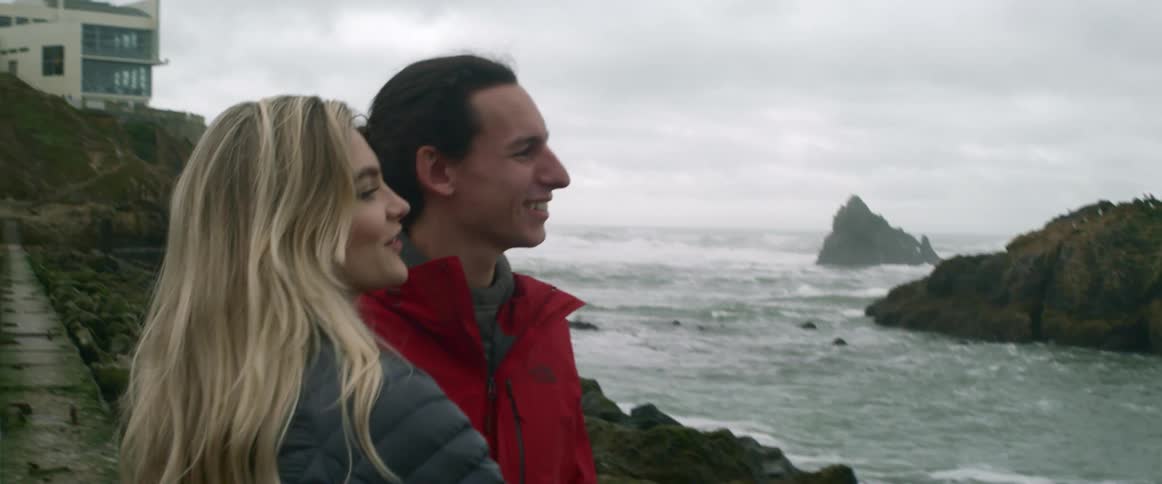 A man and woman talk together by the shore