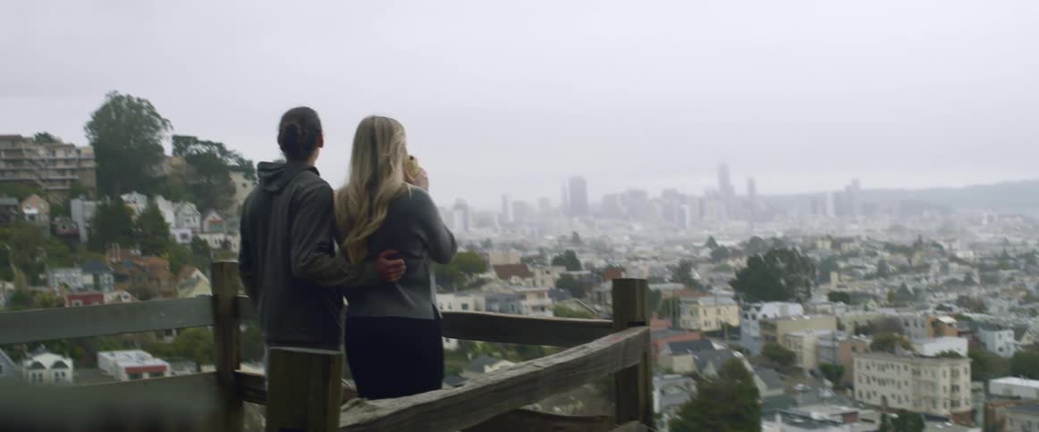 A man and woman look out at a city