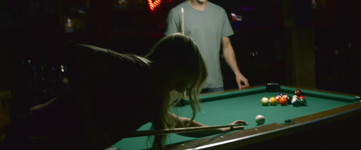 A man and woman are playing a game of pool