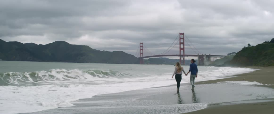 A couple walking on the beach on a cloudy day