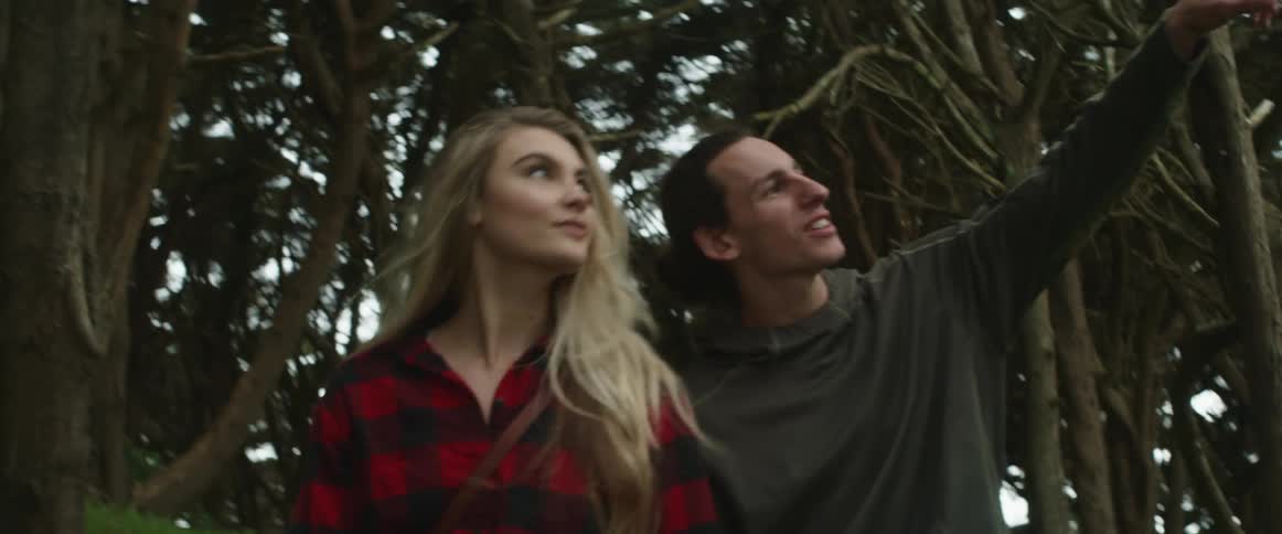 A man and woman walk in the forest together
