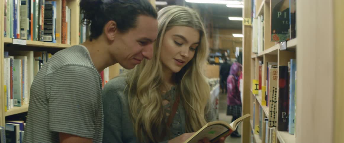 A man and woman flip through a book in a library