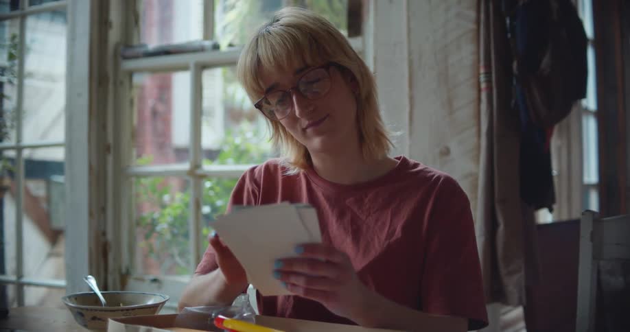 A woman in a room with glasses sitting at a table looking at photos