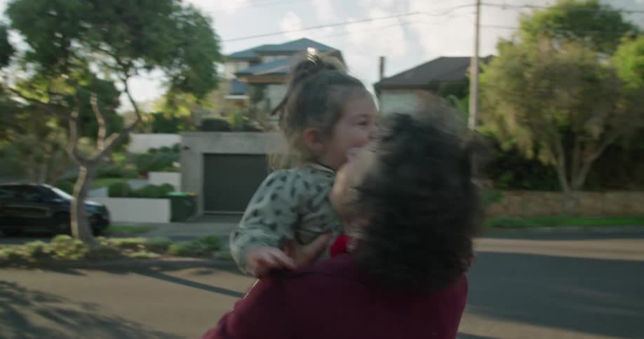 Grandmother holds the hand of her granddaughter as she walks along a ledge