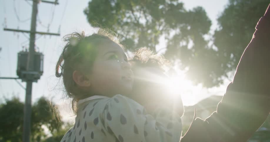 A grandmother holds a grandchild and points at something that makes them smile