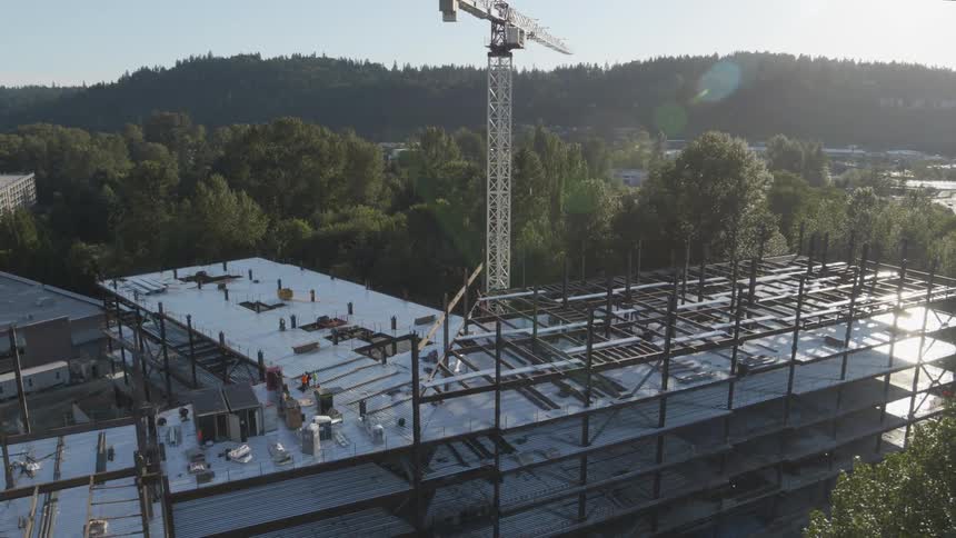 Sunshine glints off the metal framework of a new office building under construction