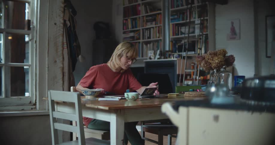 A woman in a room with glasses sitting at a table looking at a photo album