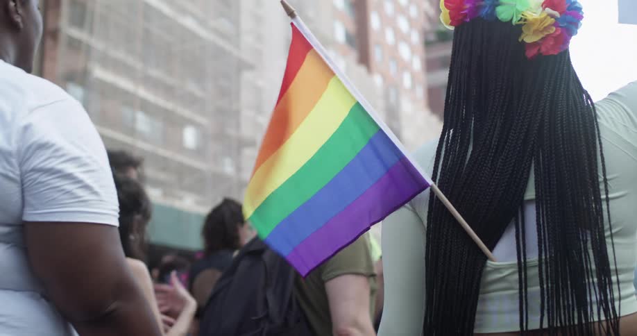 Woman carrying a rainbow flag in a city pride parade