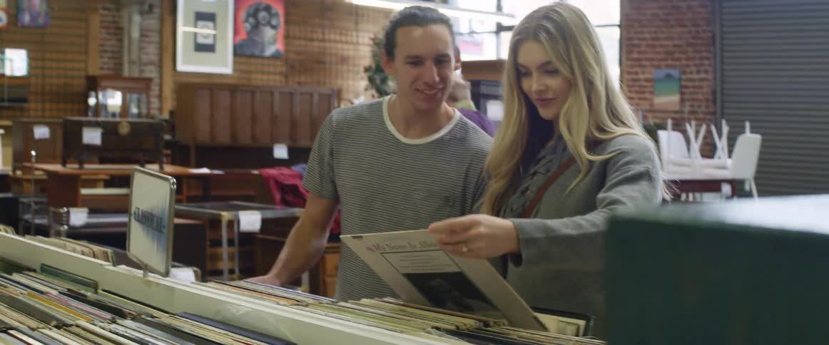 A couple talking and laughing as they look through vinyl albums in a record store