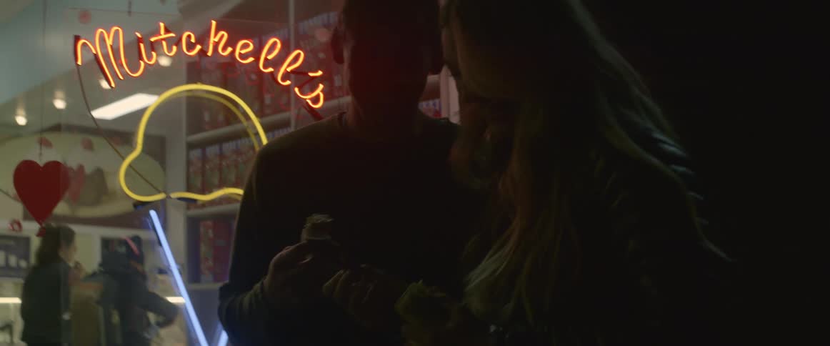 A man and woman look at photographs outside and eat ice cream
