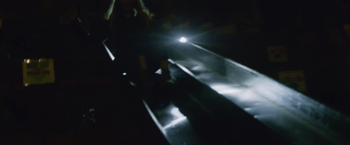 A woman slides down a slide at night