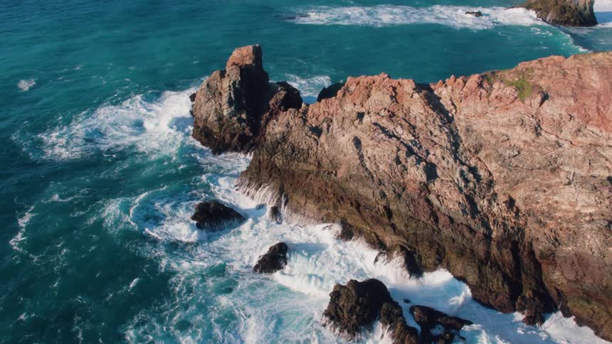 The ocean waves are crashing along the rocks