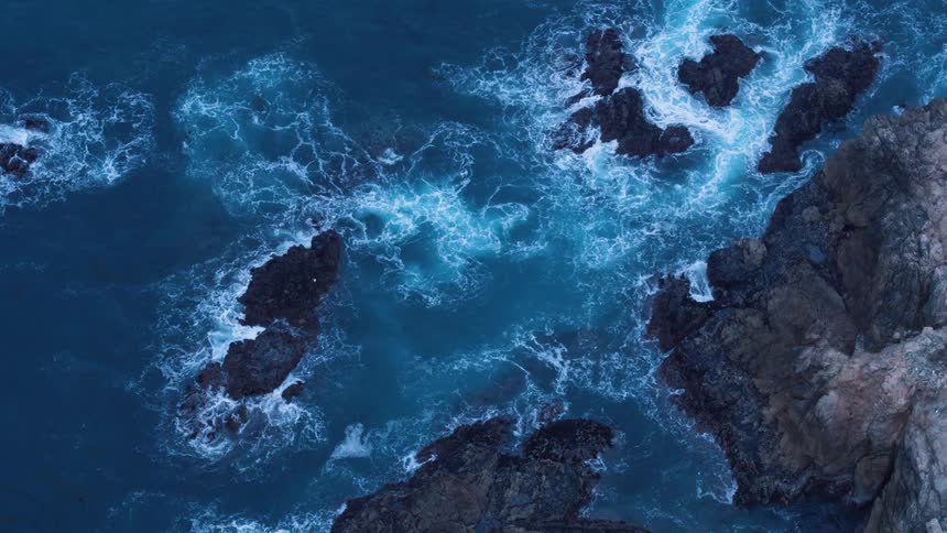 An aerial view of water crashing by the rocks