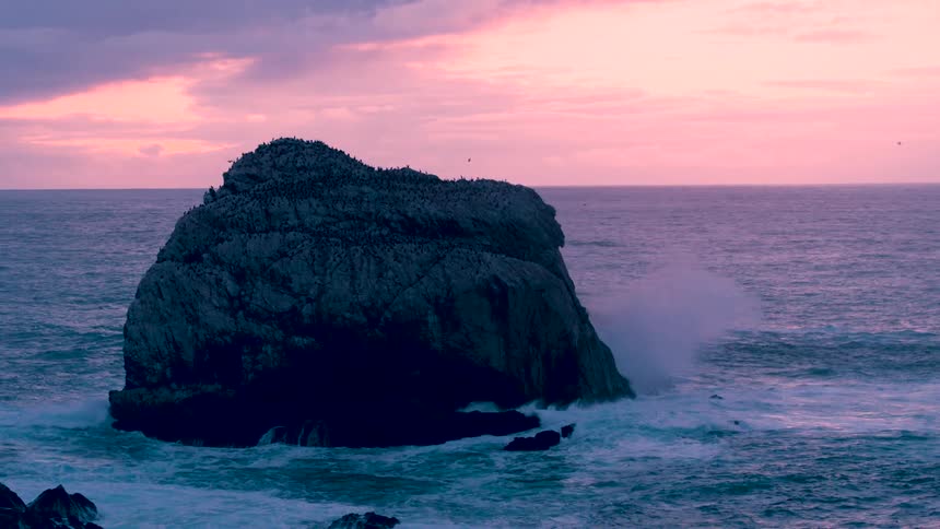 An aerial shot of a rock in an ocean