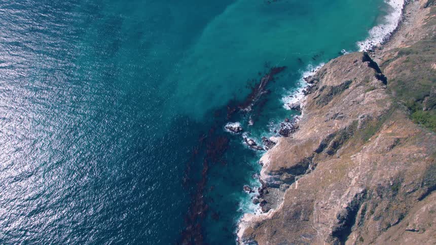 The camera flies over a rocky coast