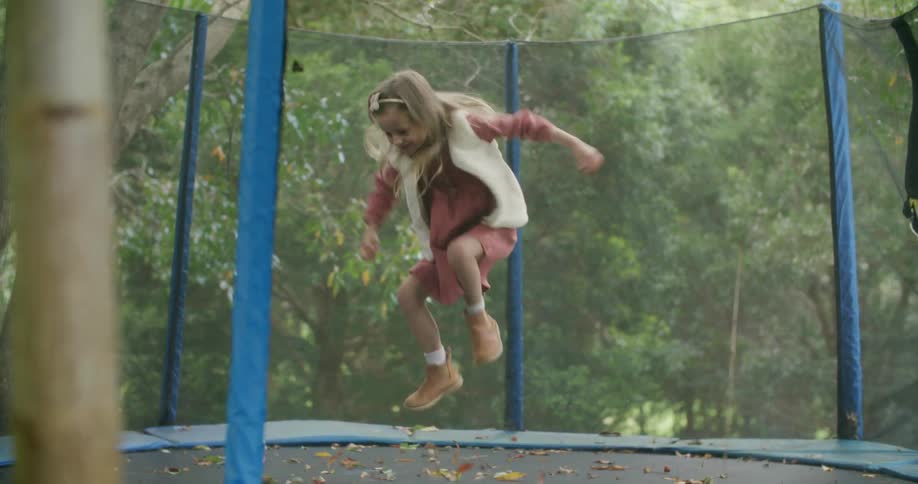 Blonde girl bounces on trampoline surrounded by protective netting