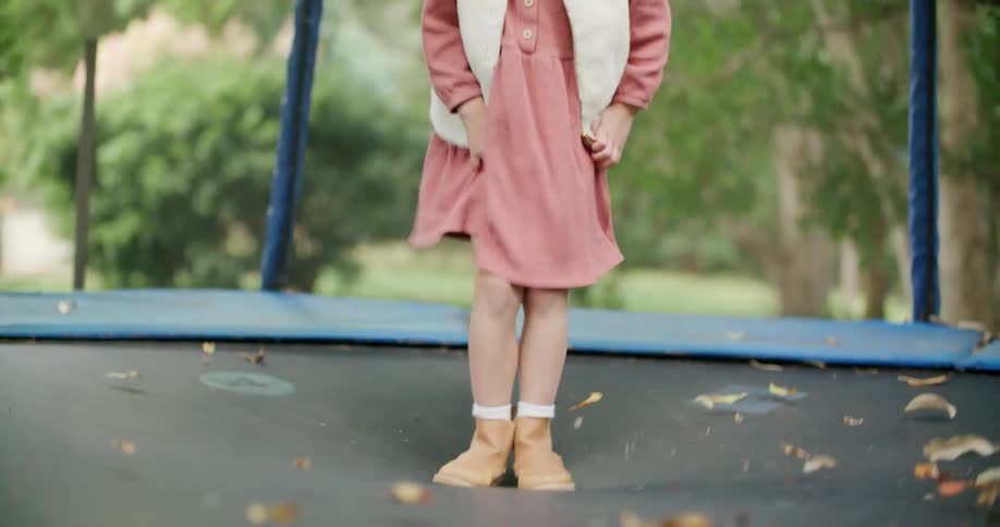A young girl jumps on a trampoline outside