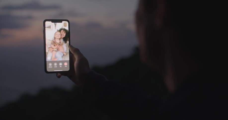 Man greeting family on a video call in a smartphone at sunset
