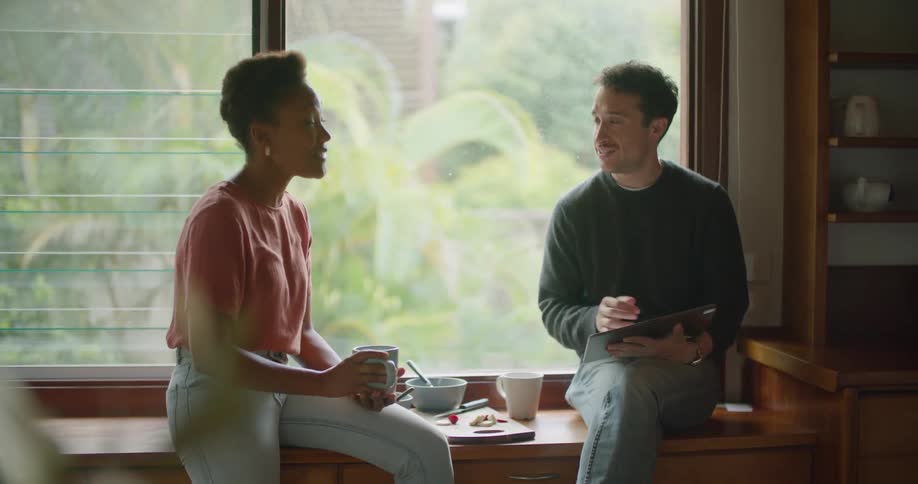 A man and woman sitting in a house talking with each other