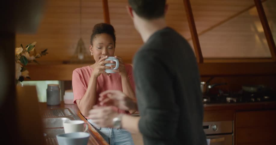 Young couple laughing and talking while making breakfast at home