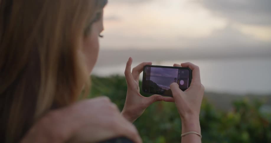 Young couples taking pictures of the landscape with a smartphone at sunset