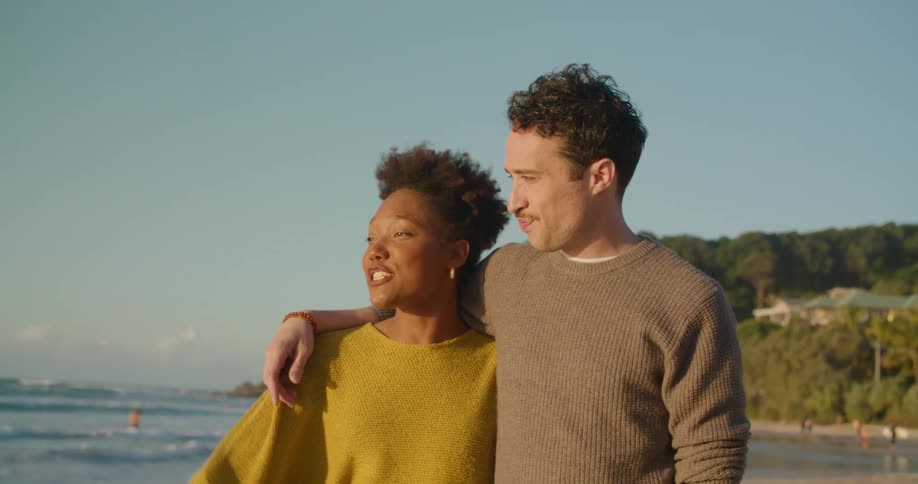 A couple walk on the beach during the day