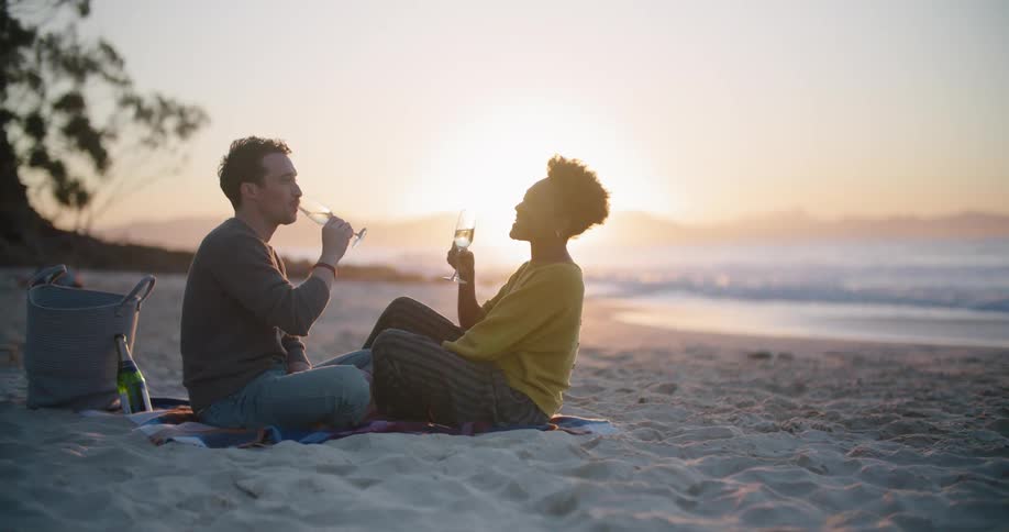A man and woman drinking wine on the beach