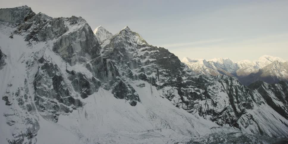 A vast, snow-covered mountain range in sunlight