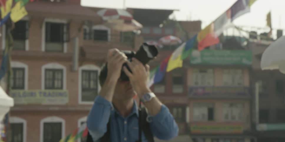 A man person lifts a camera to their face and takes pictures