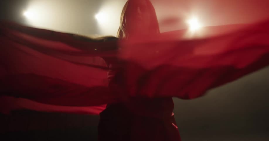 Woman with brown hair and red dress dances on stage