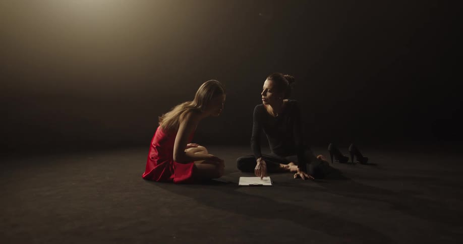 Two women talk and read from a paper on the ground