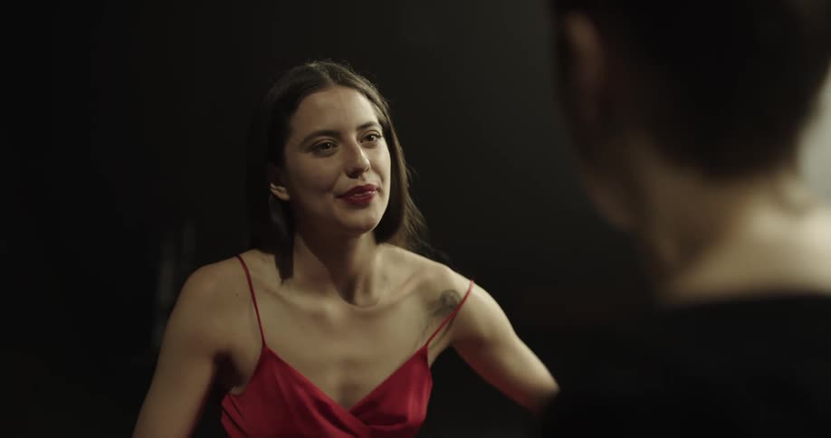Female dancer with red strappy dress talks with dance instructor